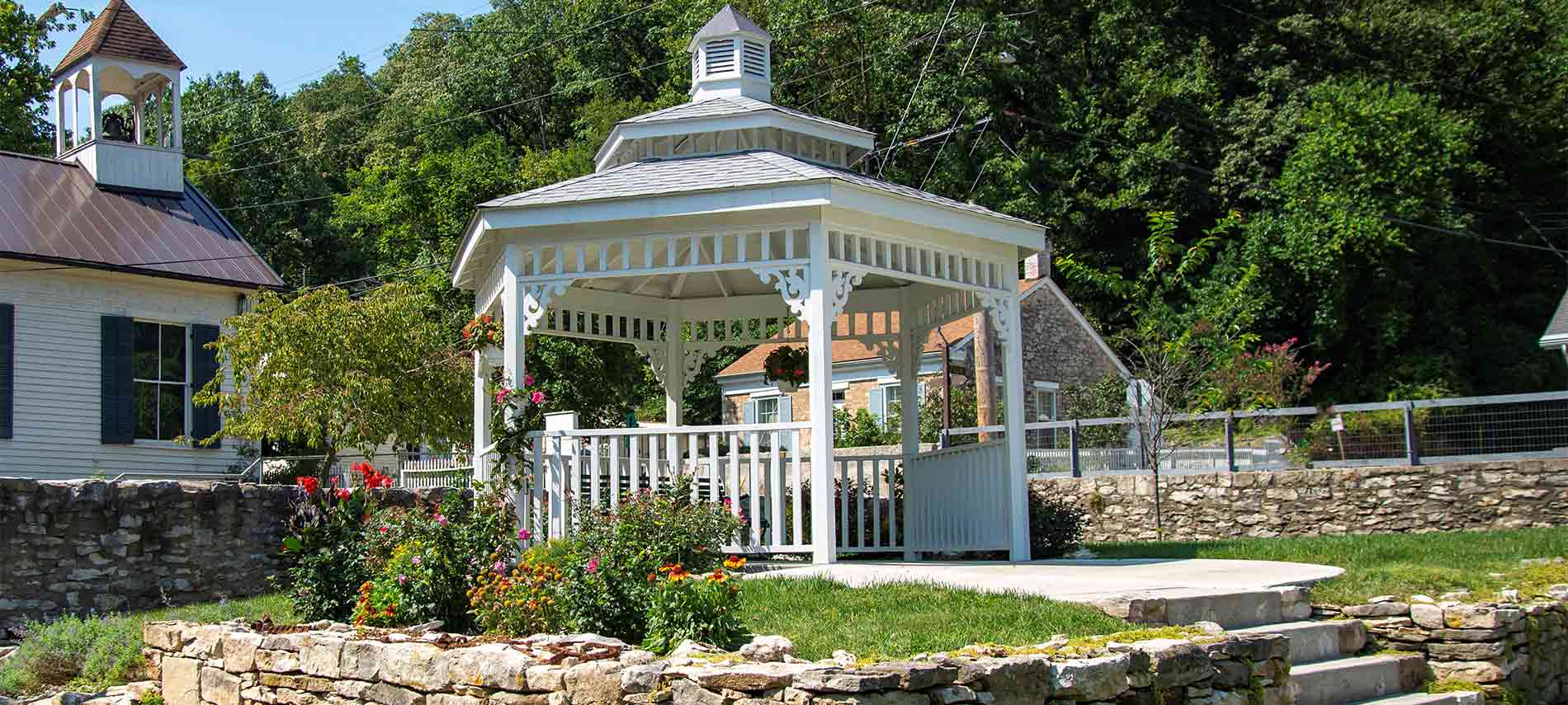 A stone lined raised gazebo with turret top and decorative sides outside the inn.