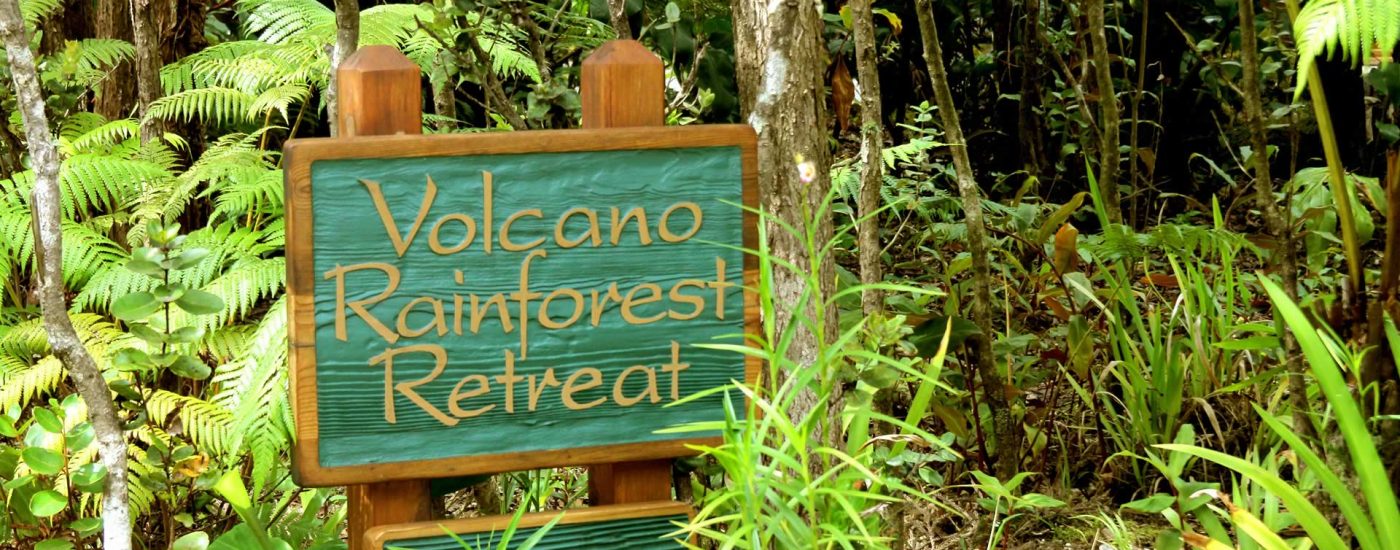 Volcano retreat sign amongh green vegetation.