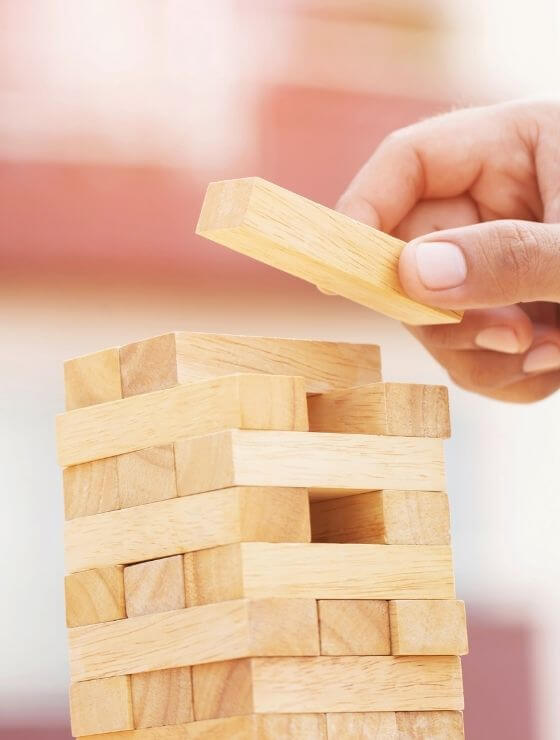 A tower of Jenga blocks with a hand adding a new block to the top.