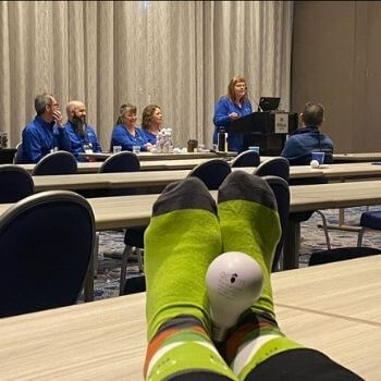 Acorn socks on feet on table at conference.