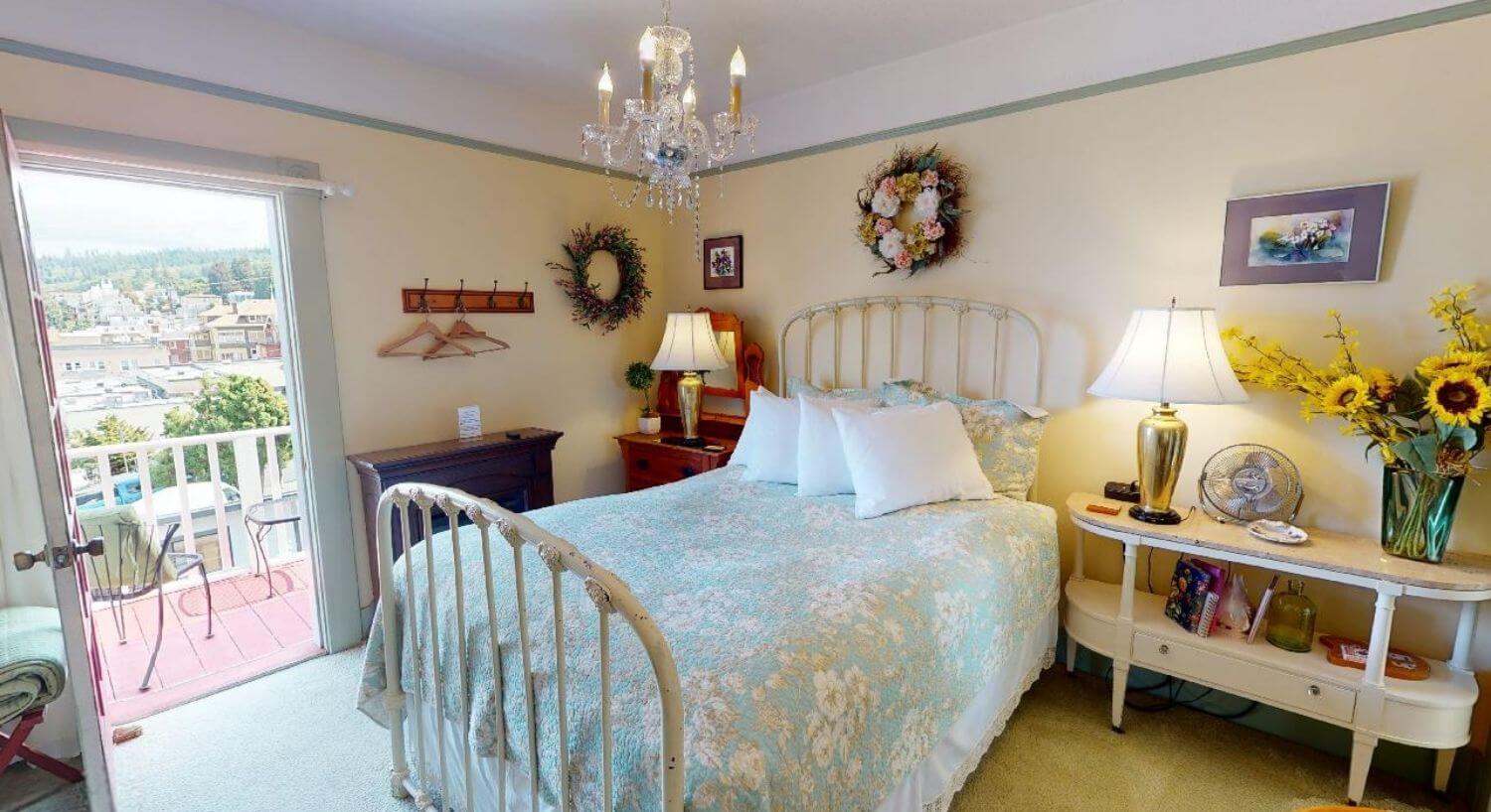 Bedroom ith white iron bed frame, decorative wreaths and chandelier
