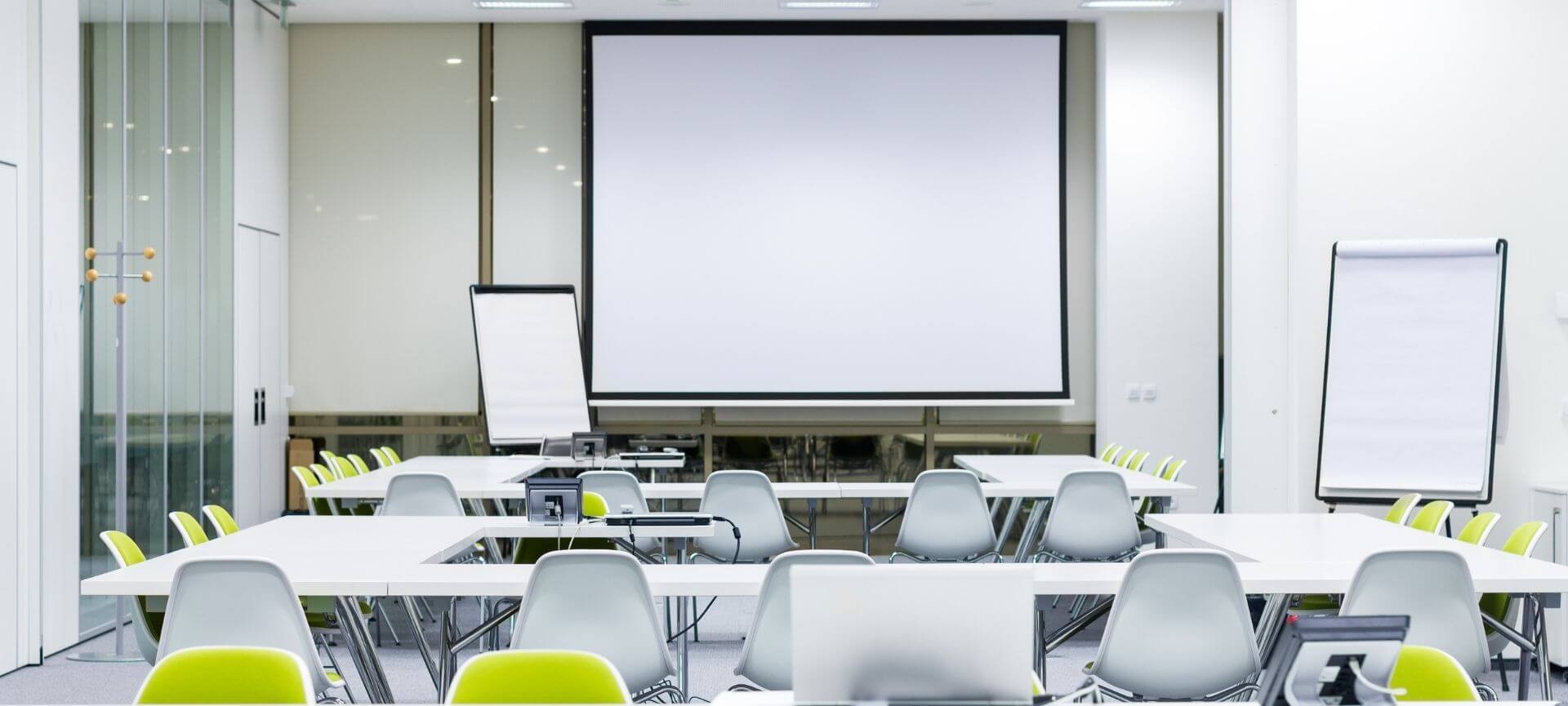 White Conference Room with big screen, tables with green chairs