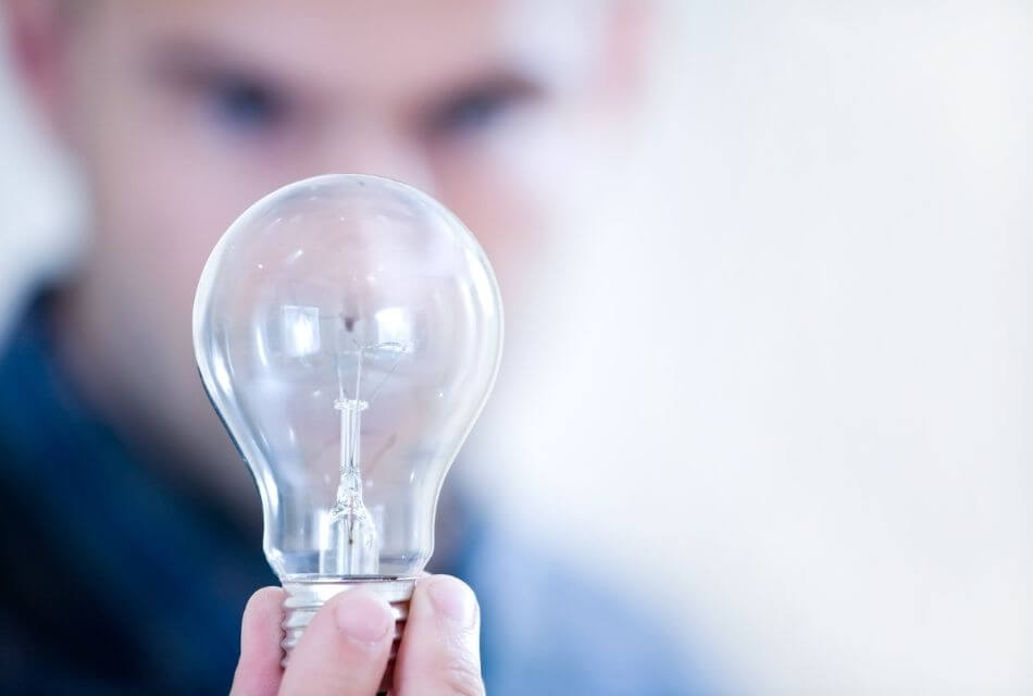 Man looks intently at lightbulb he is holding in his hand