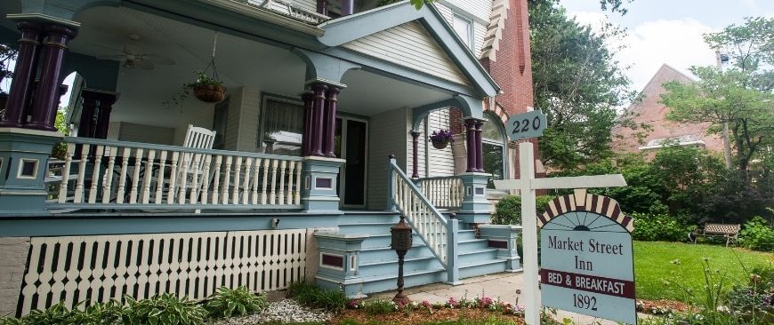 Front of Victorian house, white with teal trim, large porch with ornate railing