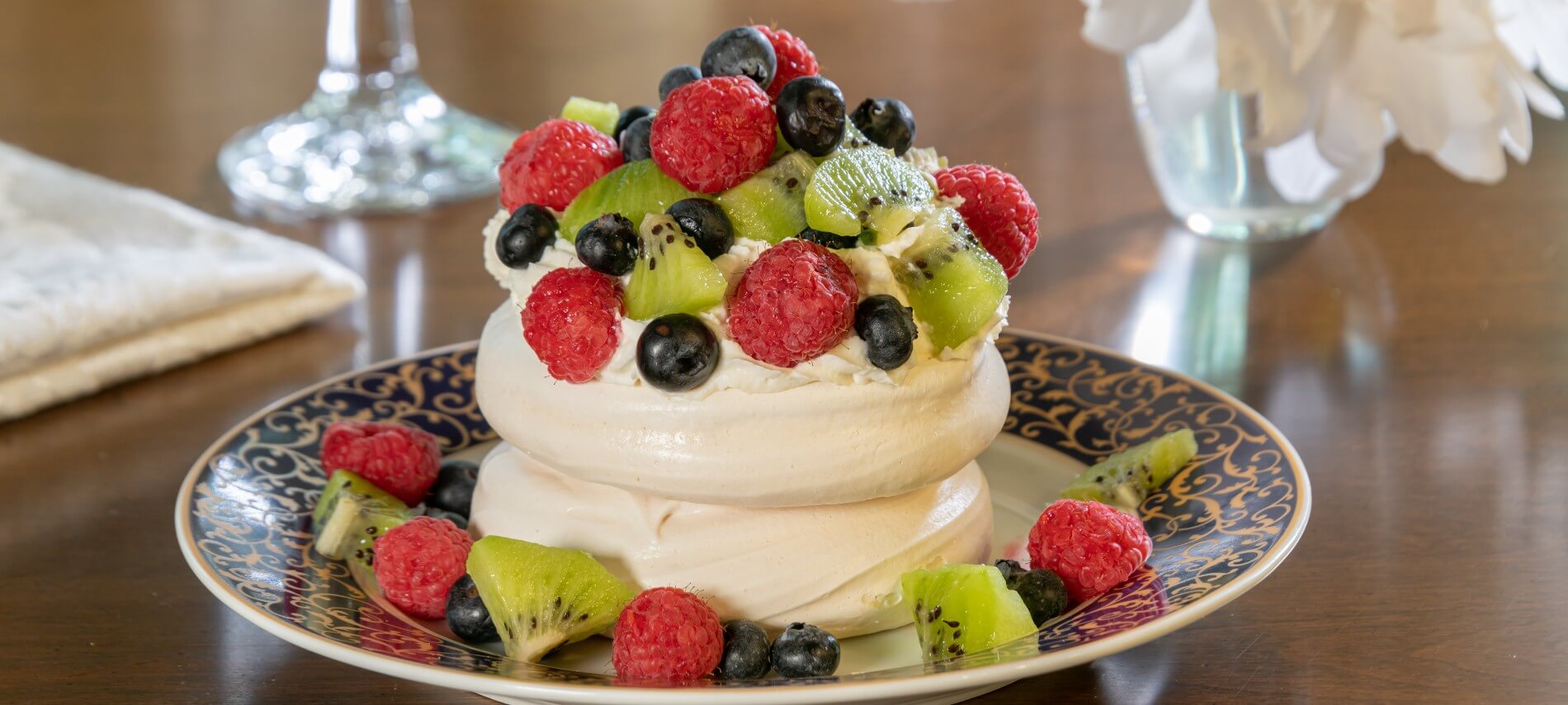 Personal-size pavlova with fruit and whipped cream on a plate