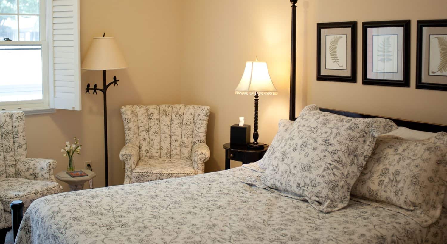 Dark wood four-post bed with floral bedding and chairs to match
