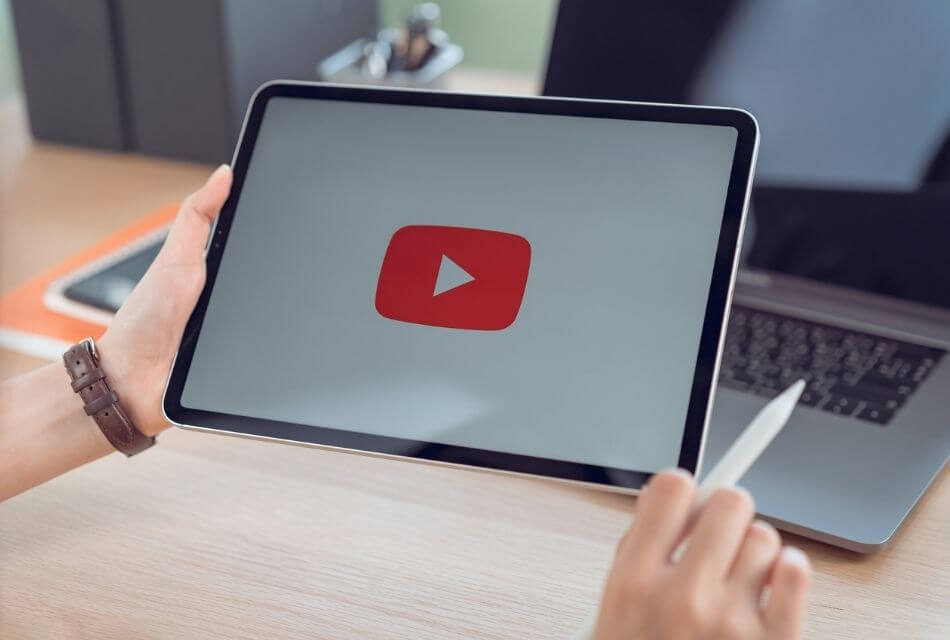 Hands holding a tablet with the YouTube logo displayed